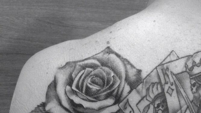 Tatuaje de una rosa y cartas terminado en la espalda.