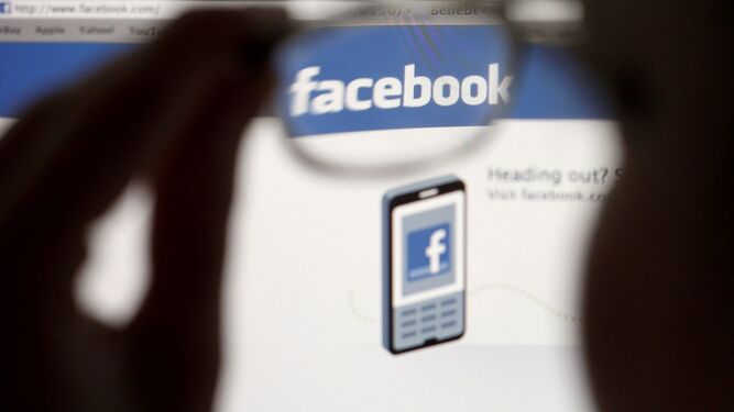 Un usuario de Facebook mira el logo de la red social a través de sus gafas.
