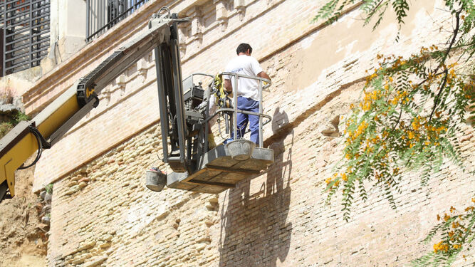 Operarios realizan obras de mejora en el muro de la iglesia de San Pedro.