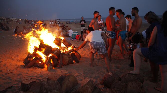 Los jóvenes avivan el fuego de la hoguera a orillas de la playa.