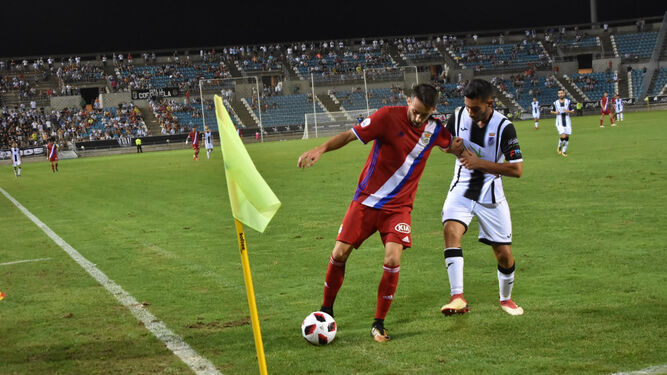 Iago Díaz retiene el cuero en la zona del banderín de córner ante la presión de un jugador del Badajoz.