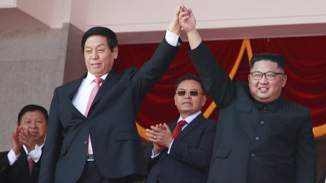 Li Zhanshu, número tres del Partido Comunista chino, y Kim Jong-un saludan en la tribuna del desfile de ayer en Pyongyang.