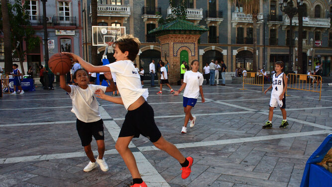 Niños juegan al baloncesto en la céntrica Plaza de las Monjas durante una fiesta dedicada al deporte.