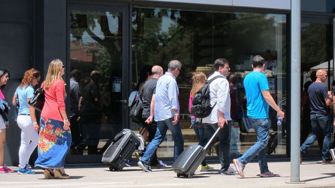 Un grupo de turistas camina hacia un hotel con sus maletas.