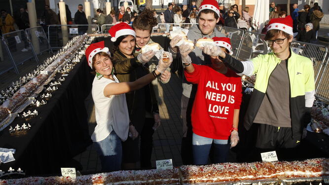 Diversos voluntarios con porciones del roscón de Reyes gigante