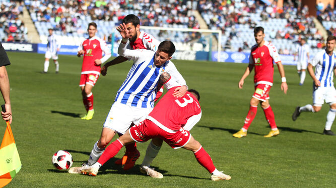 El delantero recreativista Alberto Ródenas es derribado por dos defensores del RealMurcia en un lance de la primera mitad del encuentro disputado ayer en el Nuevo Colombino.