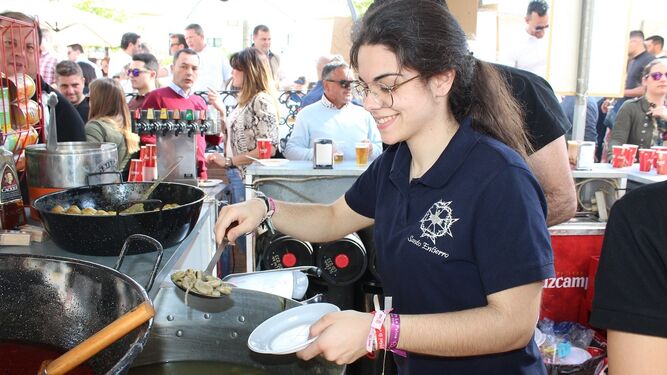 Una joven de uno de los stands sirve los platos de habas con poleo.