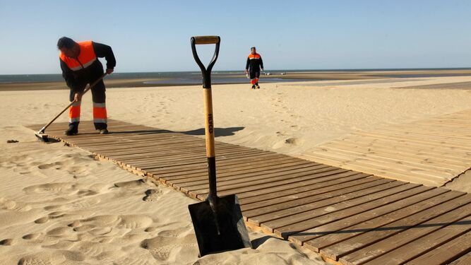 Un operario prepara una pasarela de acceso a la playa Central de Isla Cristina.
