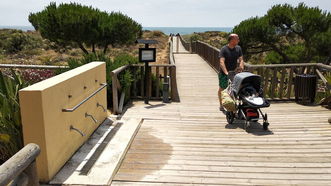 Un turista lleva un carrito de bebé por una de las pasarelas que dan acceso a una playa onubense.