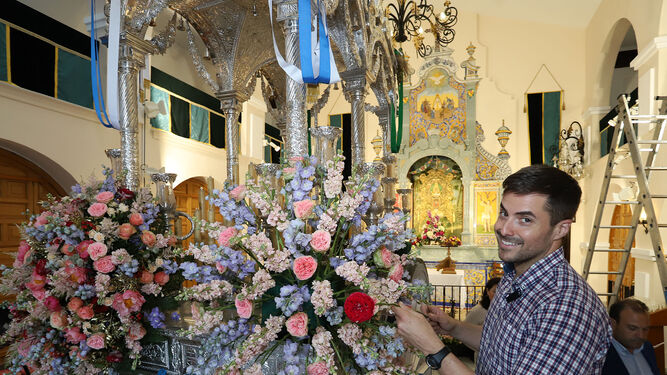Antonio Rivera coloca las flores color pastel en la carreta de plata de la Hermandad de Huelva.