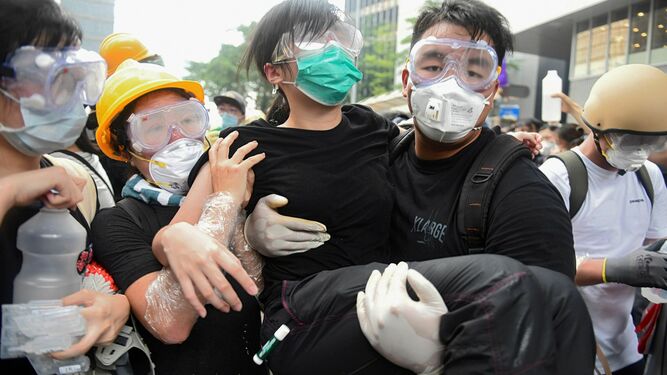 Un maanifestante recibe ayuda tras resultar afectada por el gas lacrimógeno lanzado por la policía durante las protestas en contra de la polémica ley de extradición ante el Consejo Legislativo en Hong Kong este miércoles.
