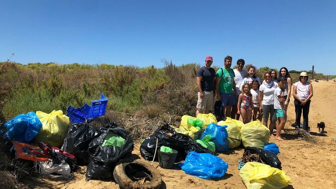 Varios voluntarios junto con los residuos recogidos durante la jornada por las playas onubenses.