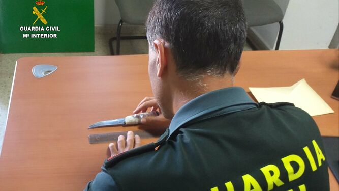 Un agente mide la hoja del cuchillo utilizado por el caco en el asalto.