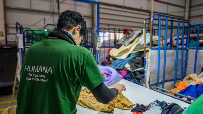 Un operario de la Fundación Humana Pueblo para Pueblo clasifica y ordena la ropa reciclada.