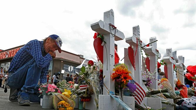 Un estadounidense se arrodilla ayer ante la cruz que honra a su pareja, Margie Reckard, asesinada el pasado domingo en el tiroteo masivo en El Paso.