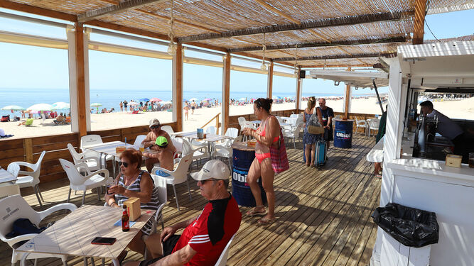 Turistas y visitantes disfrutan de los tesoros de las costa onubense en un chiringuito.