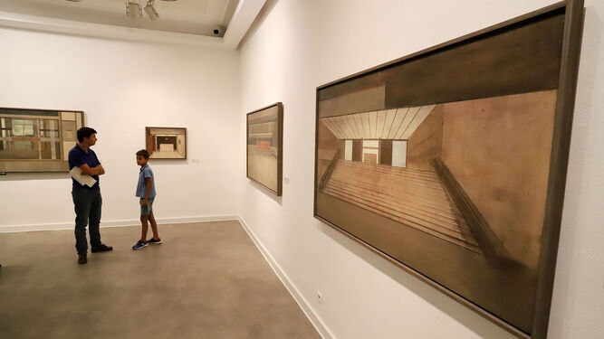 Los cuadros de una exposición realizada en el Museo de Huelva son contemplados por dos personas.
