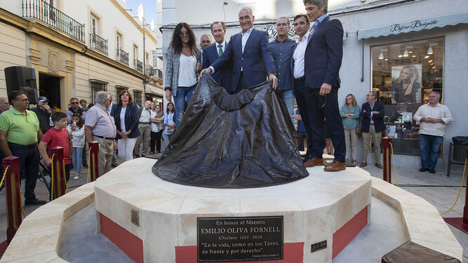 El hijo del homenajeado, Emilio Oliva Baro, sostiene el capote de bronce acompañado de familiares y el alcalde.
