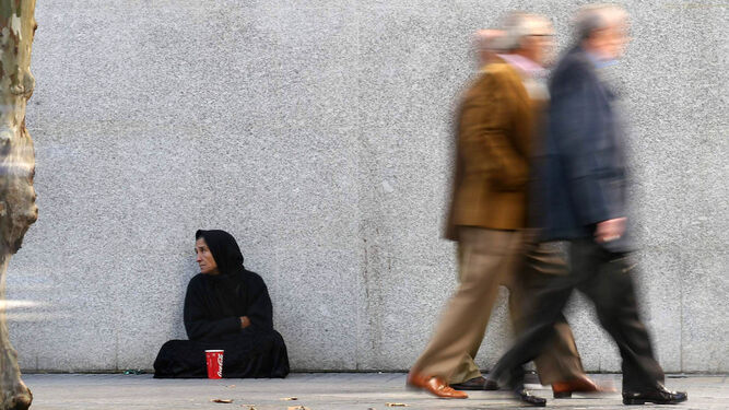 Una mujer sin hogar pidiendo en la calle.