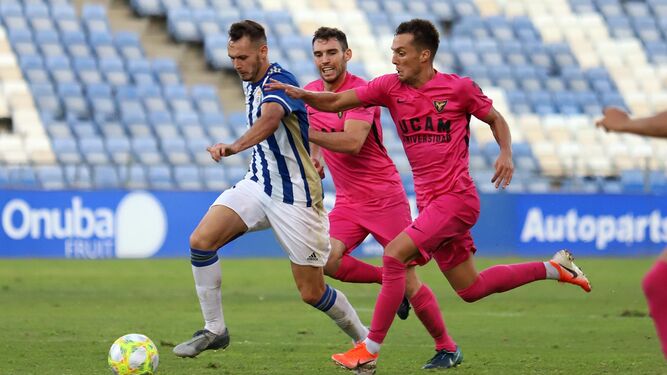 Alfonso se escapa de dos rivales en el partido ante el UCAM Murcia en el Nuevo Colombino.