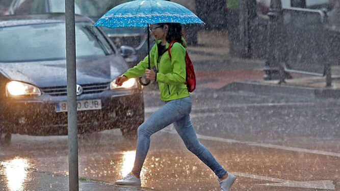 Una chica cruza una calle de la capital bajo un paraguas.