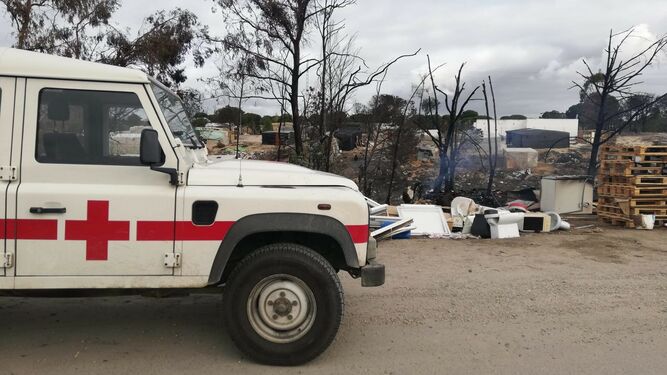 Un vehículo de Cruz Roja, junto a los restos del incendio en las chabolas de Palos.
