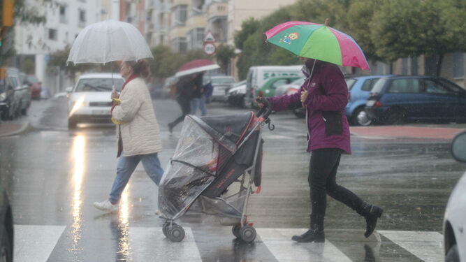 Personas caminando bajo la lluvia por la ciudad.