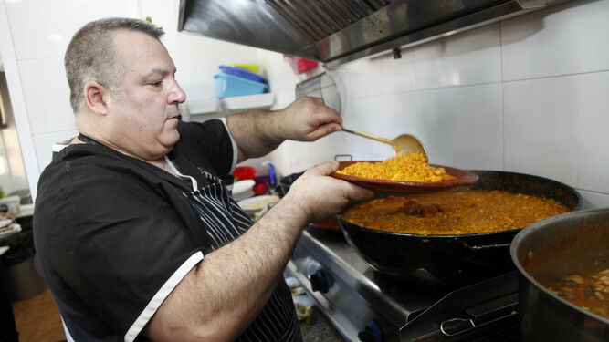 El hostelero isleño Paco Torres sirve un plato de arroz de marisco en la cocina de su establecimiento donde ha preparado un menú solidario.