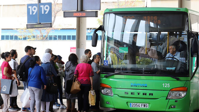 Varias personas guardan cola para subirse a un autobús en la capital onubense.