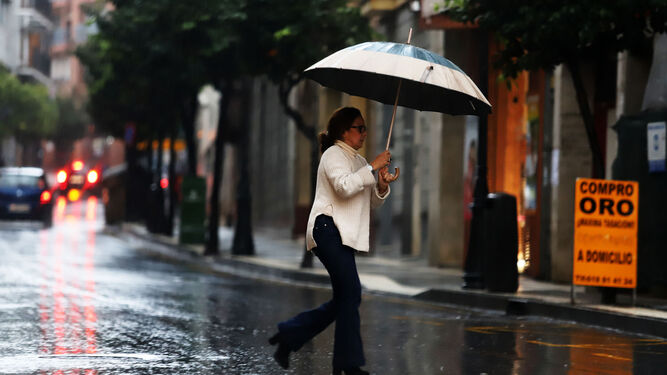 Una mujer se tapa de la lluvia con su paraguas.