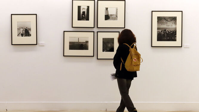 Una mujer observa algunas fotografías de la serie 'La caja de zapatos' de Gabriel Cualladó.