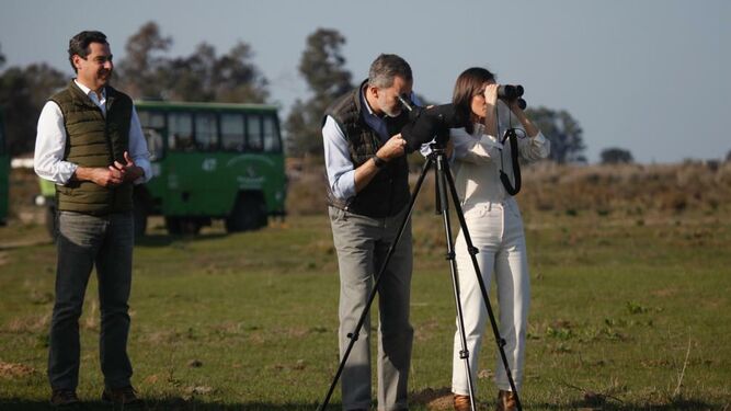 Don Felipe y Doña Letizia observan la fauna de Doñana a través de unos prismáticos acompañados por Juanma Moreno.