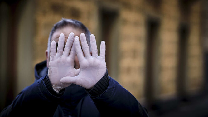 Un hombre muestra sus manos protegidas con guantes de látex
