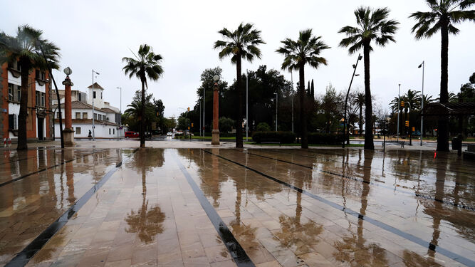 Panorámica de la plaza Doce de Octubre, en la capital onubense, vacía y con el suelo mojado convertido en espejo para las palmeras.