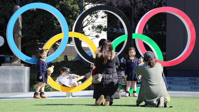 Un grupo de niños se fotografían junto a los aros olímpicos en Tokio.