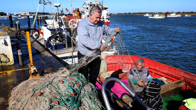 Marineros de Punta Umbria manipulan las redes de pesca.