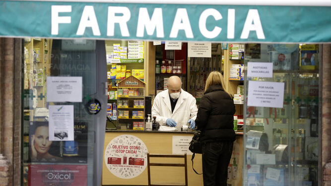 Un farmacéutico dispensa un medicamento a una usuaria.