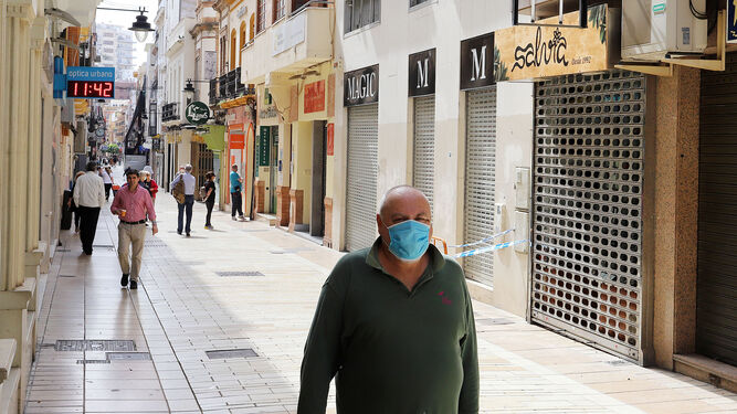 Un hombre camina por el centro de Huelva ante la mayoría de los comercios cerrados.