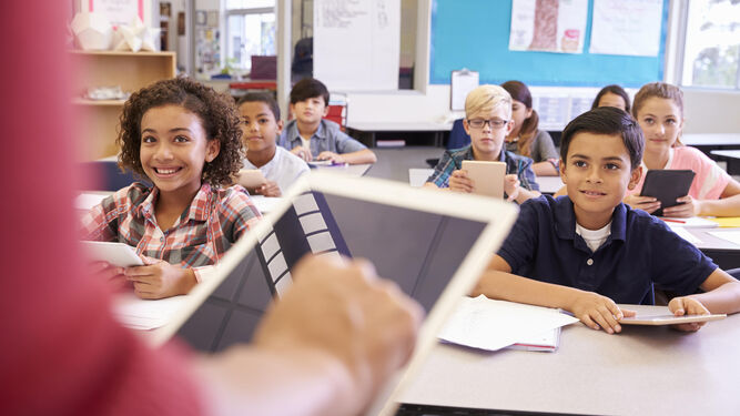 Maestra y alumnos utilizan las 'tablets' durante una clase presencial.