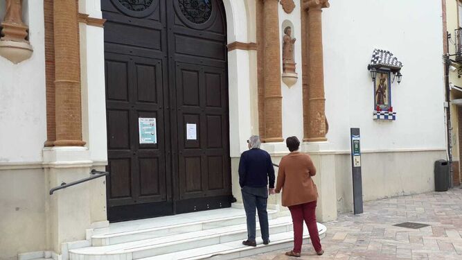 Una pareja mira los horarios de misa en la puerta de La Concepción.