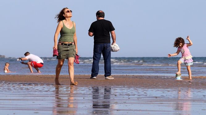 Una mujer pasea y disfruta de los rayos de sol por la playa de Punta Umbría.