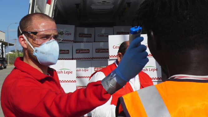 Un voluntario de Cruz Roja toma la temperatura de uno de los residentes en un asentamiento.