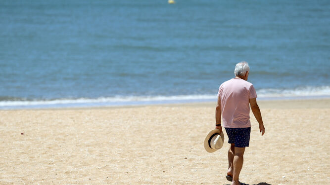 Un bañista pasea por la playa de La Antilla.