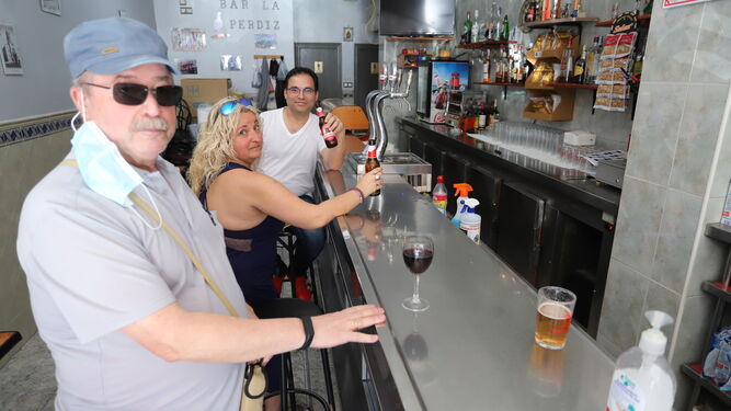Varias personas disfrutan de sus consumiciones en la barra del bar La Perdiz.