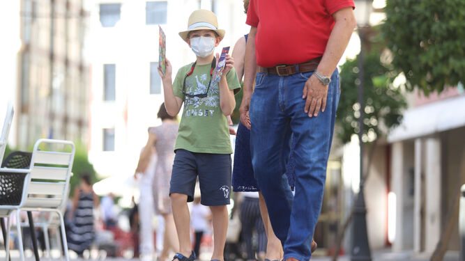 Un niño se protege del calor con un sombrero de paseo por las calles de la capital