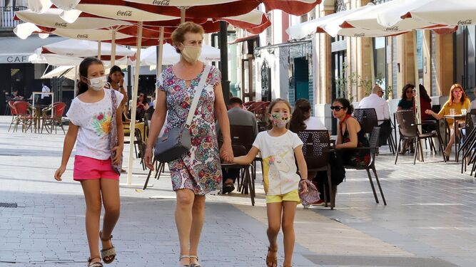 Un mujer camina por la Plaza de las Monjas junto a dos niñas, todas ellas con sus mascarillas.