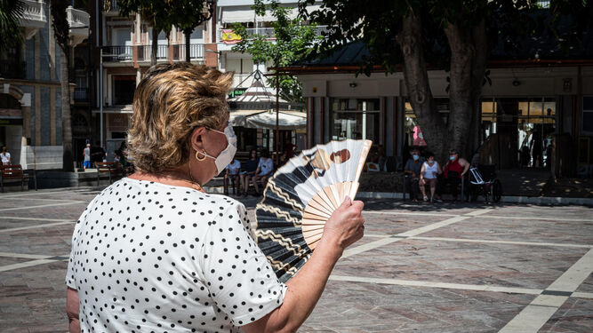 Una mujer pasea con abanico por la plaza de Las Monjas.
