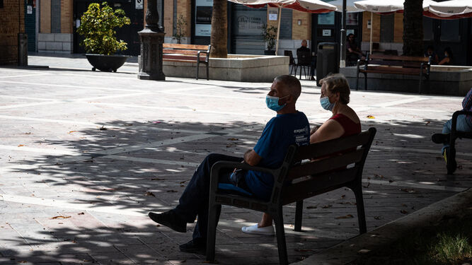 Dos personas sentadas bajo la sombra en la Plaza de las Monjas.