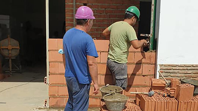Dos obreros ponen los primeros ladrillos del nuevo albergue para inmigrantes