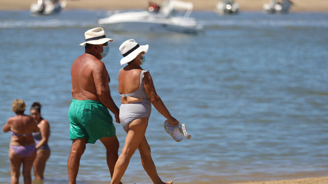 Dos personas pasean por una playa onubense.